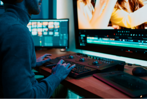 Video editor working on custom high perfromance PC setup with color grading and editing software in a modern studio